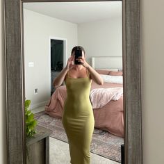 a woman taking a selfie in front of a mirror while wearing a yellow dress