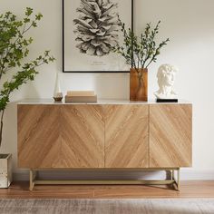 a wooden sideboard with two vases on top of it next to a plant