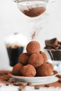 chocolate truffles being sprinkled with powdered sugar on a white plate