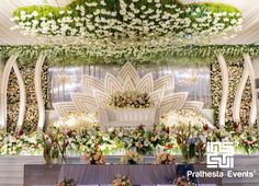 an elaborately decorated stage with flowers and greenery for a wedding or special event