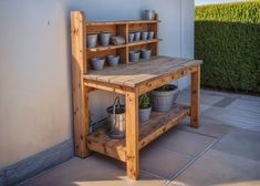 a wooden table with pots and buckets sitting on it's shelf next to a wall