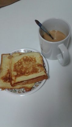 two pieces of toast on a plate next to a cup of coffee