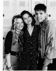 three young women standing next to each other in front of lockers, smiling at the camera