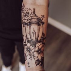 a person with a tattoo on their arm that has a lamp and flowers on it