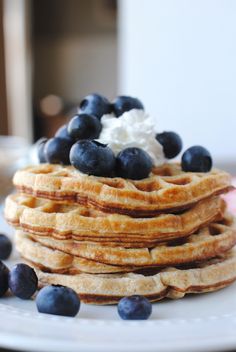 a stack of waffles topped with blueberries and whipped cream