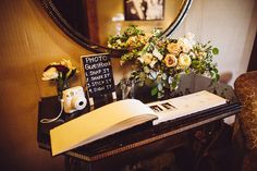 an open book sitting on top of a table next to a vase filled with flowers