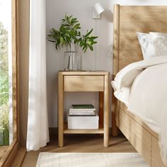 a bed room with a neatly made bed and a plant in a vase on the nightstand