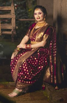 a woman in a red and gold sari sitting on steps with her legs crossed