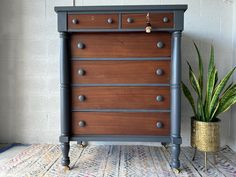 a wooden dresser sitting on top of a rug next to a potted plant