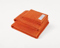 three orange towels stacked on top of each other in front of a white background,