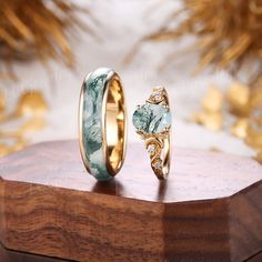 two wedding rings sitting on top of a wooden stand