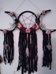 a wall hanging with flowers, feathers and other things on it's sides in the shape of a pentagram