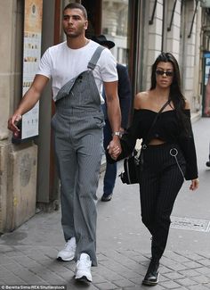 a man and woman walking down the street holding hands