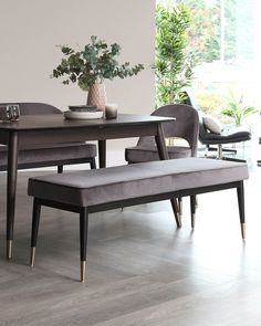 a dining room table and bench with plant in vase on the top, along with two chairs