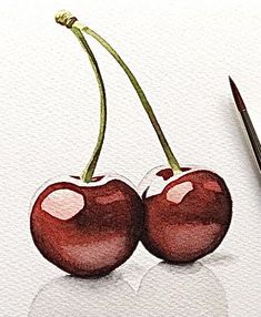 two cherries sitting on top of a white surface next to a brush and watercolor paper