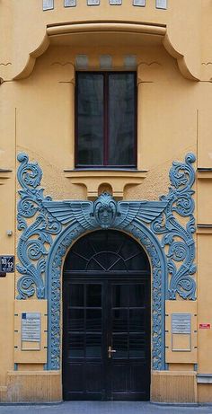 an ornate building with two black doors on the front and one blue door on the back