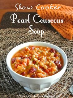 slow cooker pearl couscous soup in a white bowl on a wicker place mat