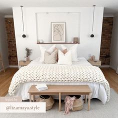 a bed with white blankets and pillows in a bedroom next to a wooden bench on the floor