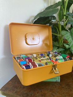 an open yellow suitcase sitting on top of a table next to a potted plant