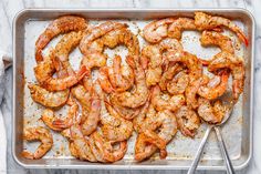 cooked shrimp on a baking sheet with tongs