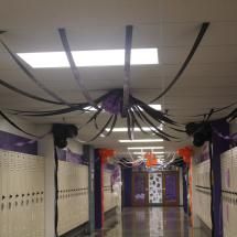 the hallway is lined with white lockers and purple ribbons hanging from the ceiling above them