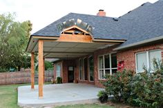 a covered patio in front of a brick house