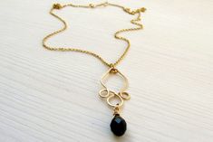 a gold necklace with a black stone hanging from it