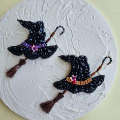 two witches hats made out of beads on a white cake with brown tassels