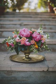 a vase filled with lots of flowers on top of a table next to some steps