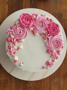 a white cake topped with pink frosting roses