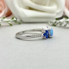 This beautiful ring is made from genuine 925 sterling silver with rhodium plating. Ring details- -The Main stone is a round cut 6mm Lab Created Light Blue Opal Stone -Side stones are 4mm by 2mm Lab Blue Sapphire Marquise and 1mm Round simulated diamonds -Ring is casted in solid 925 sterling silver with rhodium plating (yellow gold and rose gold plated also available, please check the drop down menu for more options) -The Total face height of the ring measures 7mms and the band width measures 1.5 Garnet Wedding Rings, Peridot Engagement Rings, Wedding Rings Photos, Wedding Rings Round, Simulated Diamond Rings, Art Deco Diamond Rings, Round Light, Diamonds Ring, Peridot Ring