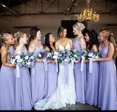 a group of women standing next to each other wearing purple dresses and holding bouquets