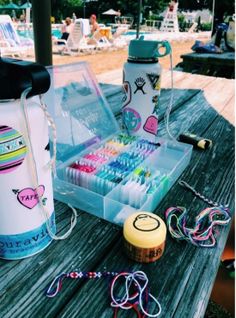 an assortment of items sitting on a picnic table next to water bottles and bracelets