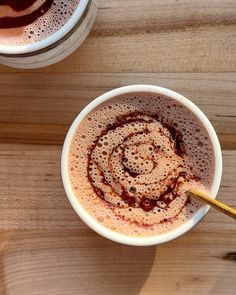 two cups filled with liquid sitting on top of a wooden table