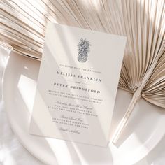 a white plate topped with an open book next to a palm fronde fan