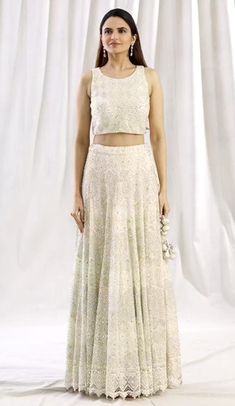 Ivory lehenga with floral embroidered motifs, paired with embroidered blouse and dupatta, featuring a round neckline, sleeveless design, side tassel tie-up, and a back cutout. Ivory Lehenga, Embroidered Motifs