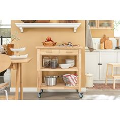 a kitchen cart with dishes on it in front of a counter and chairs around the table