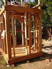 a small wooden structure sitting in the middle of a yard with lots of wood around it