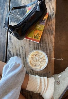 a doll is sitting next to a bag and some food on a wooden table in front of it