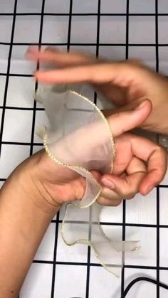 two hands holding something on top of a white tiled floor next to a wire rack