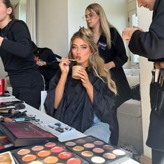 a woman is getting her hair done while others look on in the mirror behind her