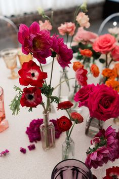 several vases filled with flowers on top of a white table covered in pink and red flowers