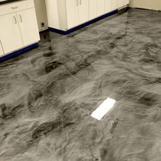 a kitchen with white cabinets and gray marble flooring that looks like it has been stained