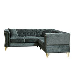 a gray velvet sectional sofa with gold studding on the legs and backrests