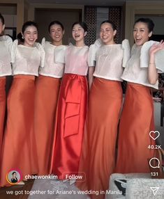 a group of women standing next to each other in front of a mirror with their hands up