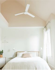 a white bed sitting under a ceiling fan