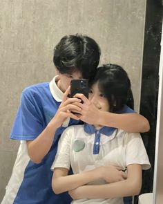 a man and woman taking a selfie in front of a mirror with their arms around each other