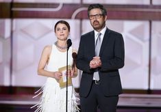 a man and woman standing next to each other in front of a microphone on stage