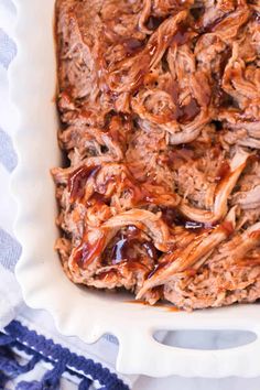 a casserole dish with pulled pork and bbq sauce in it on a blue and white tablecloth