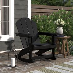 a black rocking chair sitting on top of a wooden deck next to a potted plant